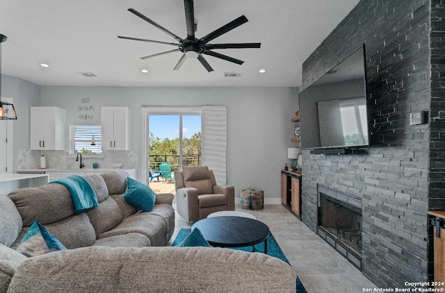 living room with ceiling fan, sink, and a fireplace