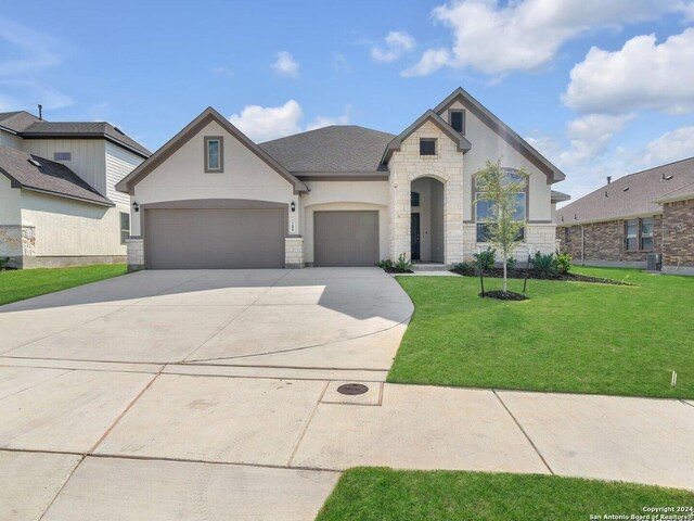 french country style house featuring a garage and a front lawn