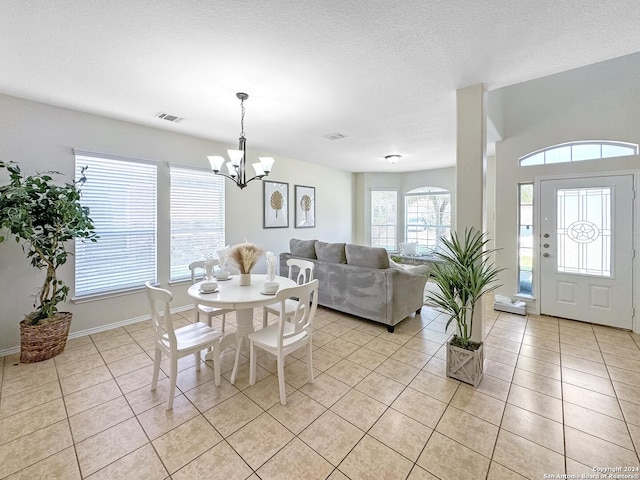 tiled dining room featuring a textured ceiling and a notable chandelier