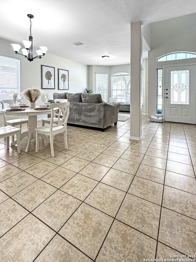 tiled foyer featuring a textured ceiling and an inviting chandelier