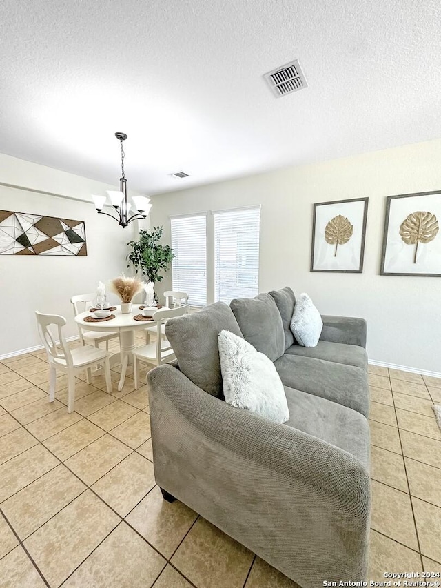 tiled living room featuring a textured ceiling and an inviting chandelier