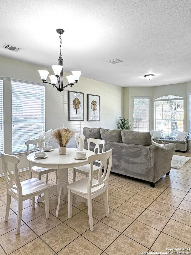 tiled dining area with a textured ceiling and an inviting chandelier