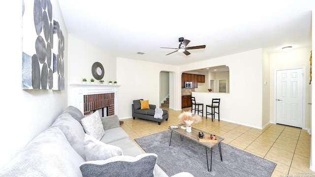 tiled living room featuring ceiling fan and a fireplace