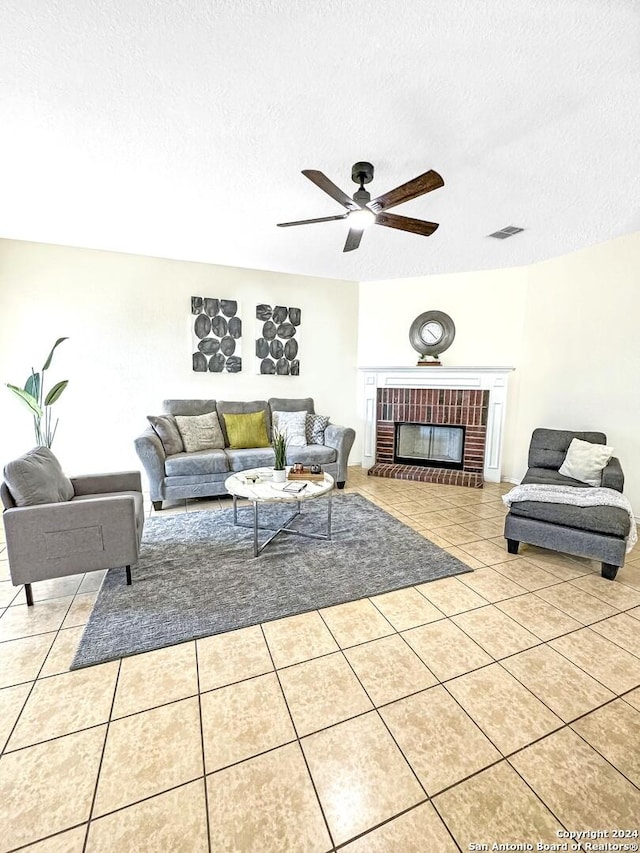 tiled living room featuring ceiling fan, a fireplace, and a textured ceiling