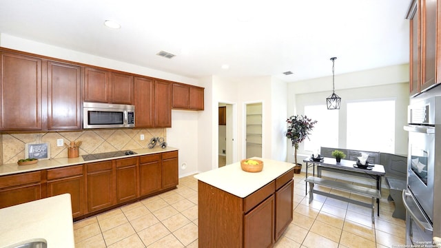 kitchen with light tile patterned floors, pendant lighting, black electric cooktop, decorative backsplash, and a kitchen island