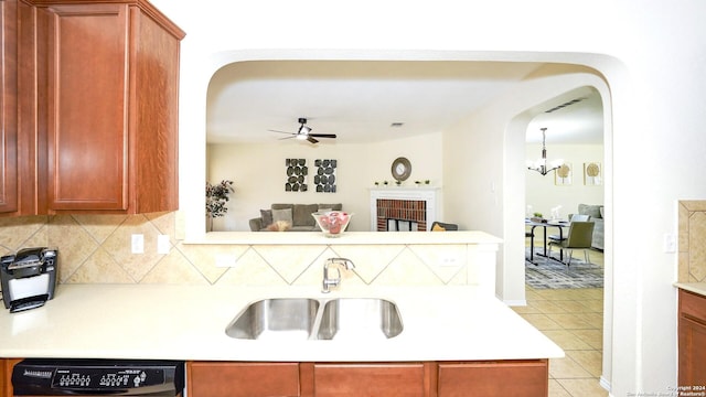 kitchen featuring backsplash, dishwashing machine, ceiling fan with notable chandelier, sink, and light tile patterned flooring