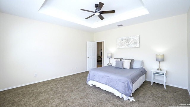 bedroom featuring a tray ceiling, ceiling fan, and dark carpet