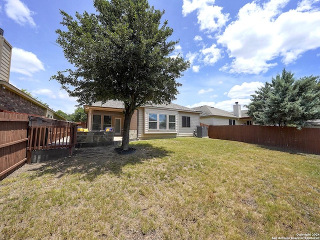 rear view of house featuring central AC and a yard