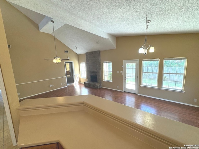 kitchen featuring a fireplace, ceiling fan with notable chandelier, a textured ceiling, wood-type flooring, and hanging light fixtures