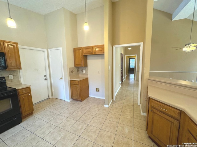 kitchen featuring black appliances, a textured ceiling, ceiling fan, and a high ceiling