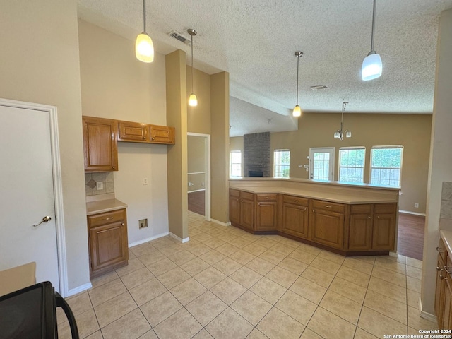 kitchen with a textured ceiling, pendant lighting, light tile patterned floors, backsplash, and high vaulted ceiling