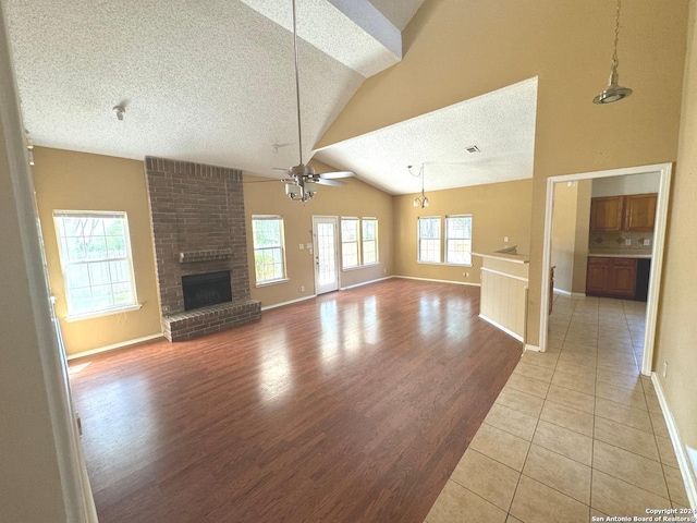 unfurnished living room with a textured ceiling, a fireplace, light hardwood / wood-style floors, plenty of natural light, and ceiling fan