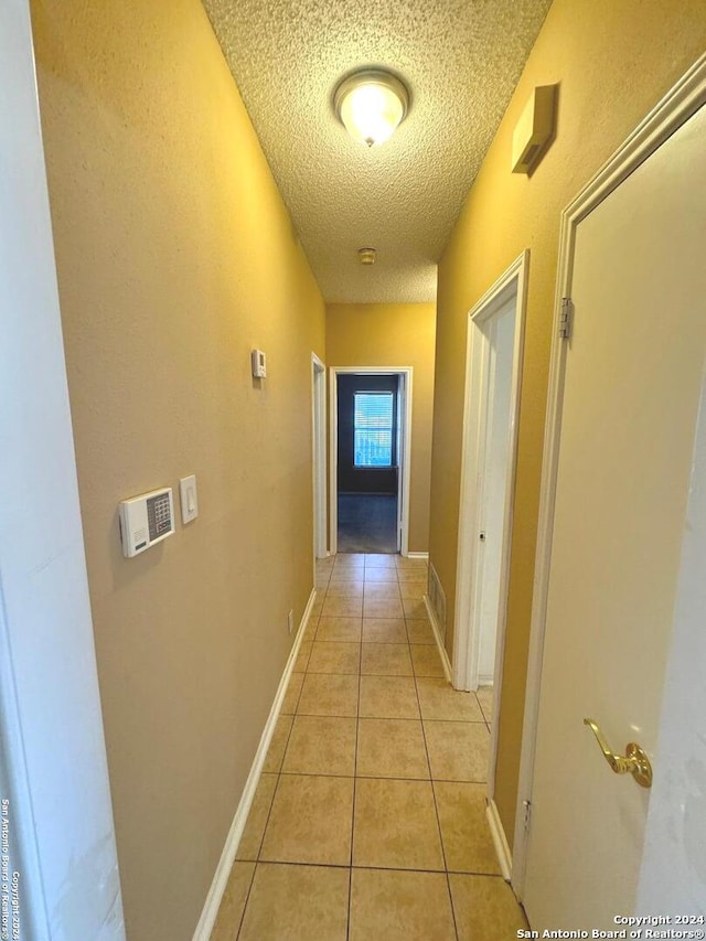 hall featuring light tile patterned flooring and a textured ceiling