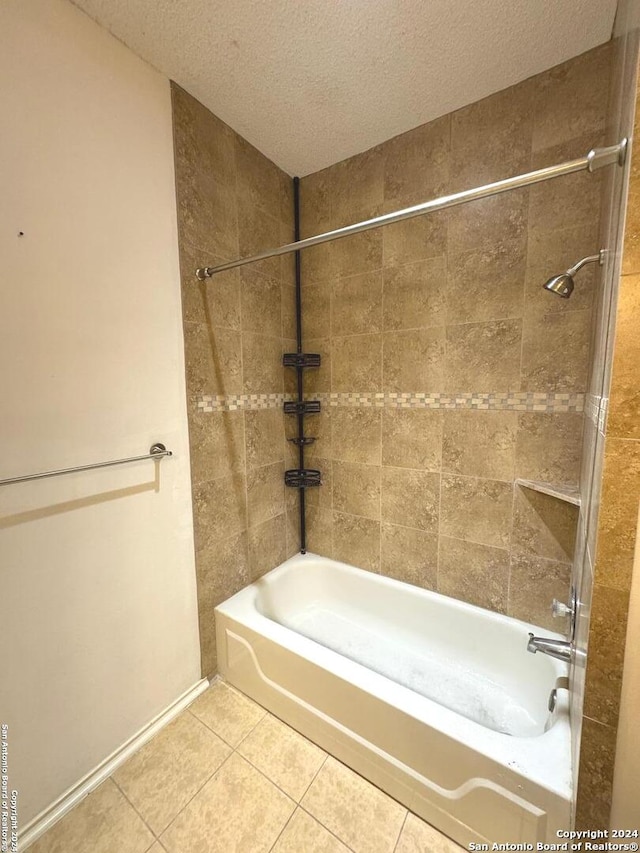 bathroom with a textured ceiling, tiled shower / bath combo, and tile patterned flooring