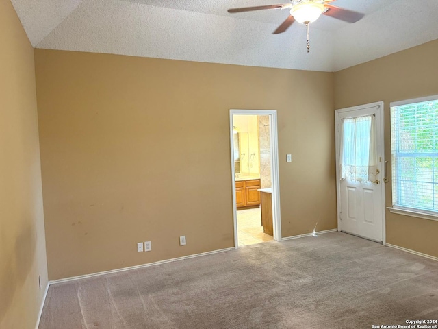 unfurnished room with vaulted ceiling, light colored carpet, and ceiling fan