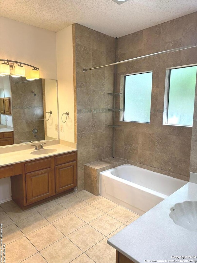 bathroom with a textured ceiling, vanity, tiled shower / bath, and tile patterned floors