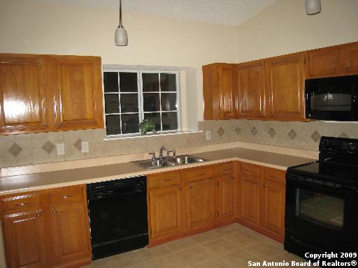 kitchen with decorative light fixtures, black appliances, sink, decorative backsplash, and vaulted ceiling