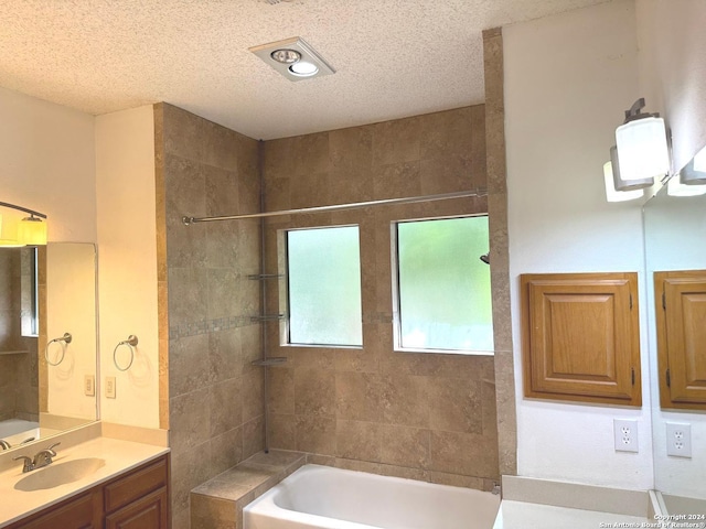 bathroom featuring tiled shower / bath, a textured ceiling, and vanity