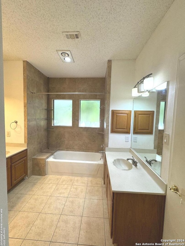 bathroom featuring tiled shower / bath combo, vanity, a textured ceiling, and tile patterned flooring