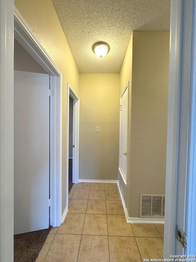 hallway with light tile patterned floors and a textured ceiling