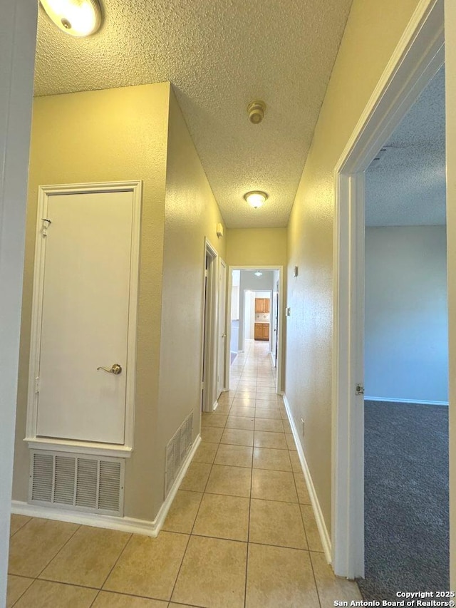 hall featuring light tile patterned floors and a textured ceiling