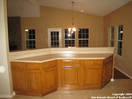 kitchen with lofted ceiling, decorative light fixtures, light tile patterned floors, and a notable chandelier