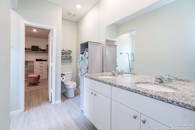 bathroom with hardwood / wood-style flooring, toilet, and double sink vanity