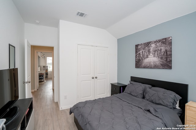 bedroom featuring vaulted ceiling, a closet, and light wood-type flooring