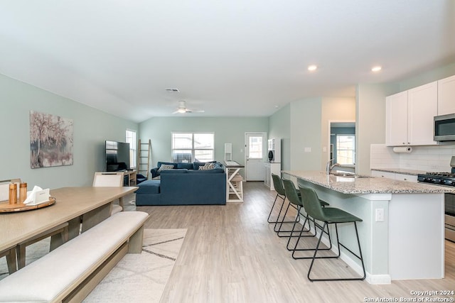 kitchen with decorative backsplash, a breakfast bar area, appliances with stainless steel finishes, light stone counters, and a sink