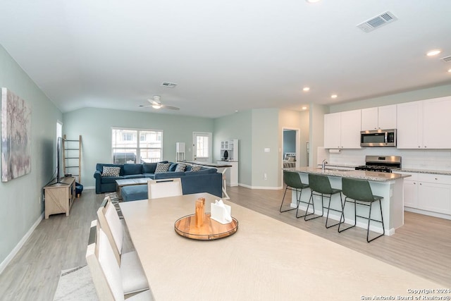 dining room featuring light wood-style flooring, visible vents, and baseboards