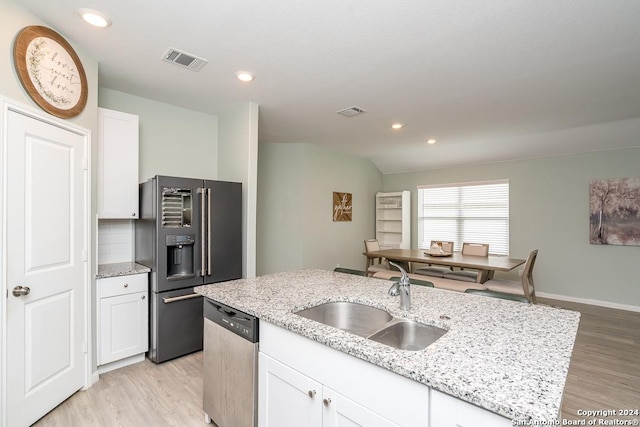 kitchen with tasteful backsplash, stainless steel dishwasher, white cabinets, a sink, and black fridge