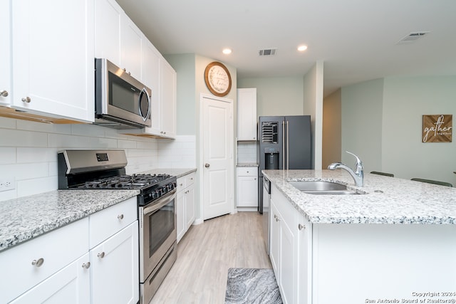 kitchen with light stone counters, stainless steel appliances, light hardwood / wood-style floors, decorative backsplash, and sink