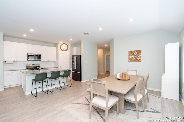 dining room with light wood finished floors, baseboards, visible vents, and recessed lighting