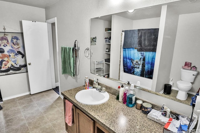 bathroom with toilet, vanity, and tile patterned floors