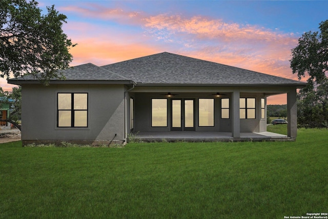 back house at dusk with a patio, a yard, and ceiling fan