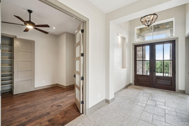 foyer featuring french doors, ceiling fan with notable chandelier, and light wood-type flooring