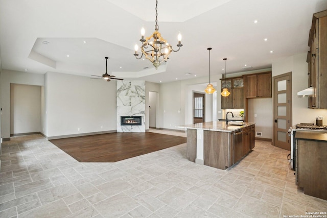 kitchen with a large island, pendant lighting, stainless steel appliances, light stone countertops, and a raised ceiling