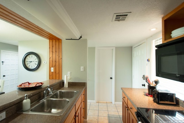 kitchen featuring sink, a textured ceiling, black microwave, and light tile patterned floors