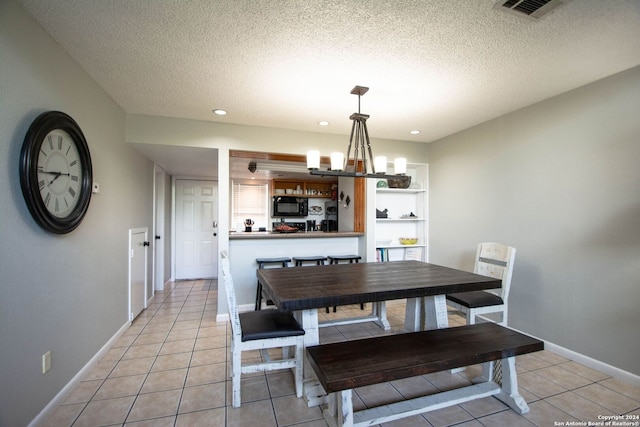 tiled dining space with an inviting chandelier and a textured ceiling