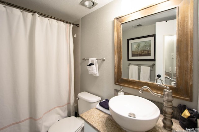 bathroom with vanity, toilet, and a textured ceiling