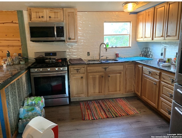 kitchen featuring sink, dark stone counters, appliances with stainless steel finishes, and dark hardwood / wood-style flooring