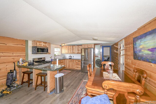 dining room with sink, wood walls, dark hardwood / wood-style floors, and lofted ceiling