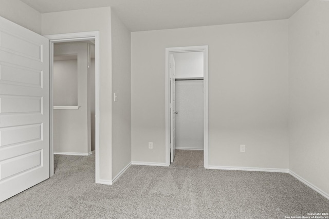 unfurnished bedroom featuring a closet, a spacious closet, and light carpet