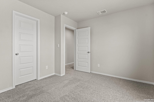 unfurnished bedroom with light carpet and a closet