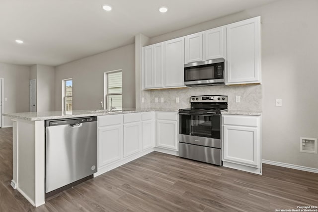 kitchen with sink, white cabinetry, light stone counters, kitchen peninsula, and stainless steel appliances