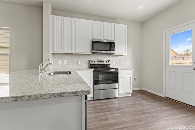 kitchen with light stone counters, appliances with stainless steel finishes, sink, and white cabinets