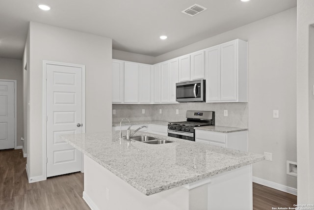 kitchen with light stone countertops, stainless steel appliances, backsplash, white cabinets, and sink