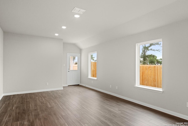 spare room featuring wood-type flooring, vaulted ceiling, and a wealth of natural light