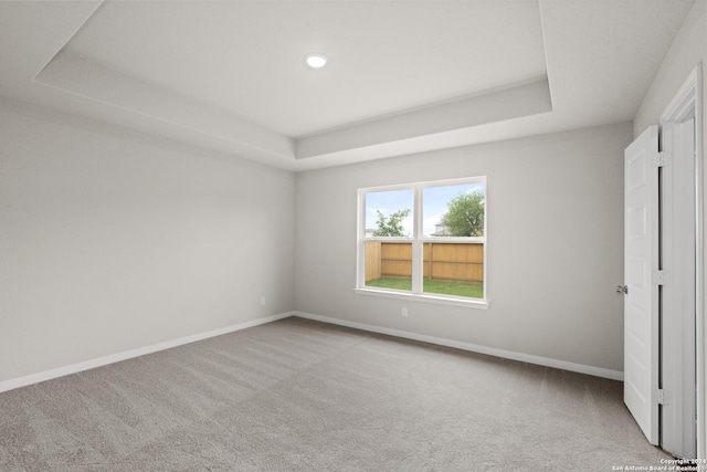 unfurnished bedroom with a tray ceiling and light carpet