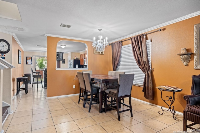 dining space featuring light tile patterned flooring, ornamental molding, a textured ceiling, and a chandelier